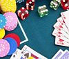 image of card table showing cards, dice, and poker chips on the table.